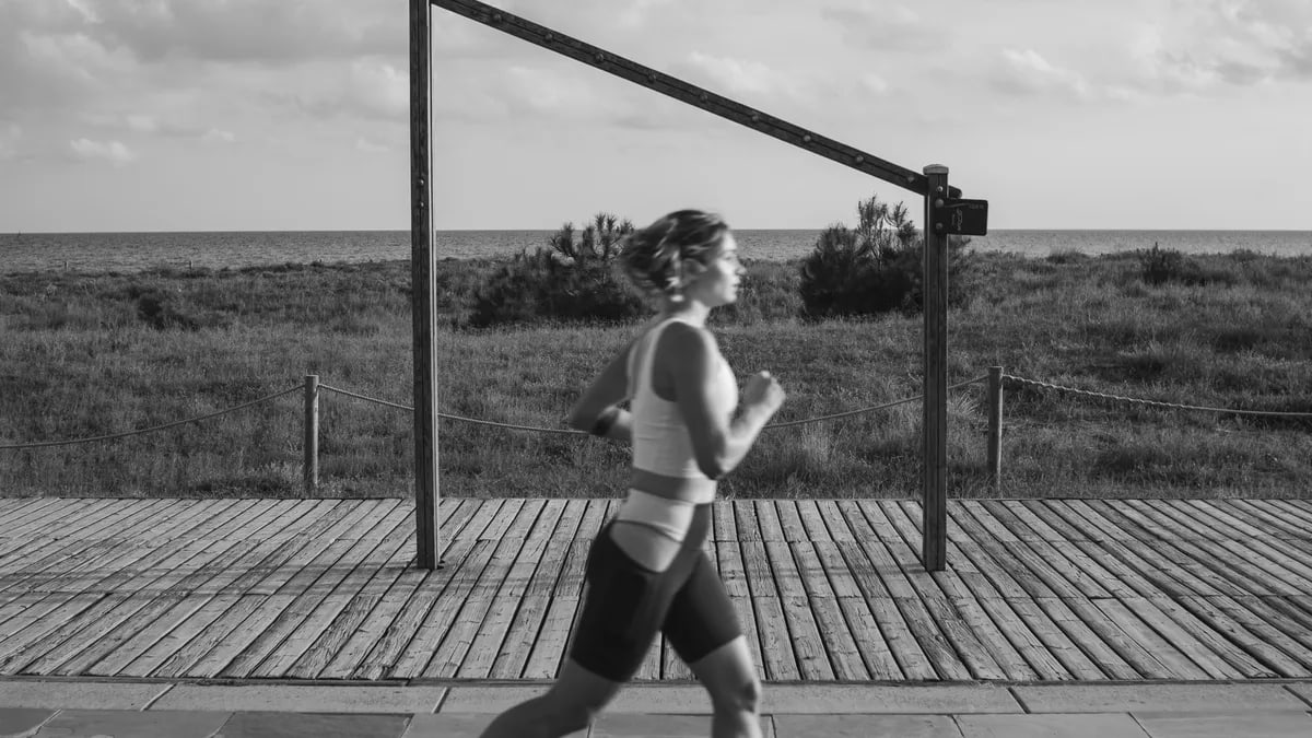 A woman jogs along a coastal boardwalk in Castelldefels, Spain, promoting fitness and outdoor exercise.